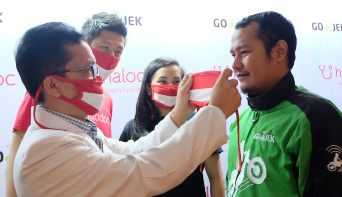 dr. Irwan Heryanto, MARS, Chief Medical Halodoc memasangkan masker kepad...
