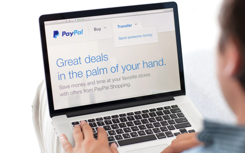 man sitting the MacBook retina with site PayPal on screen Password PayPal