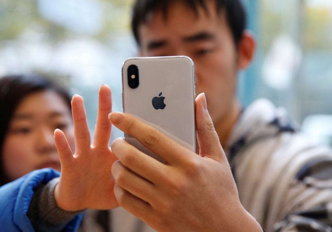 Customers look at Apple's new iPhone X after it goes on sale at the Apple Store in Tokyo