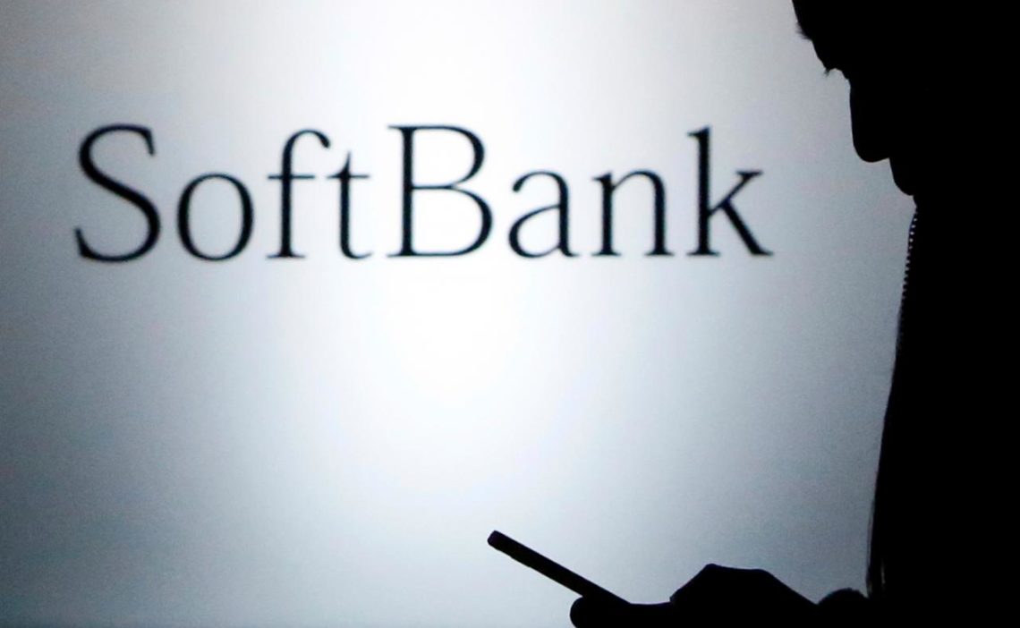 FILE PHOTO - A pedestrian holding a mobile phone walks past a logo of SoftBank Corp in front of its branch in Tokyo