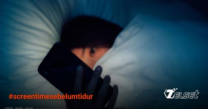 Ilustrasi seseorang menggunakan ponsel di tempat tidur di malam hari