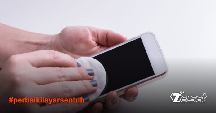 Orang sedang membersihkan layar ponsel dengan kain microfiber