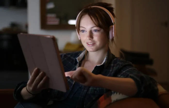 Wanita menggunakan iPad untuk merekam audio dengan headphone