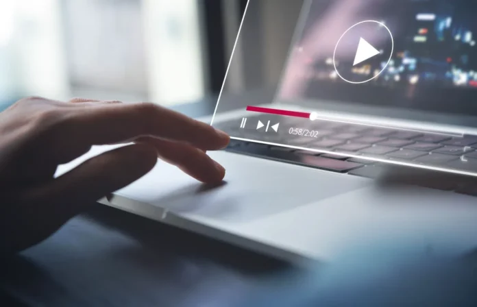 Tangan mengoperasikan laptop dengan tampilan pemutaran video YouTube