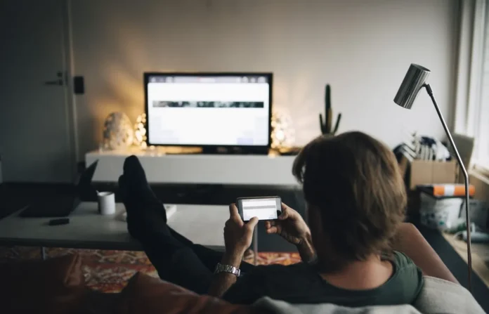 image-1755404556877-4337.webp Orang menggunakan smartphone sambil menonton TV dengan Chromecast
