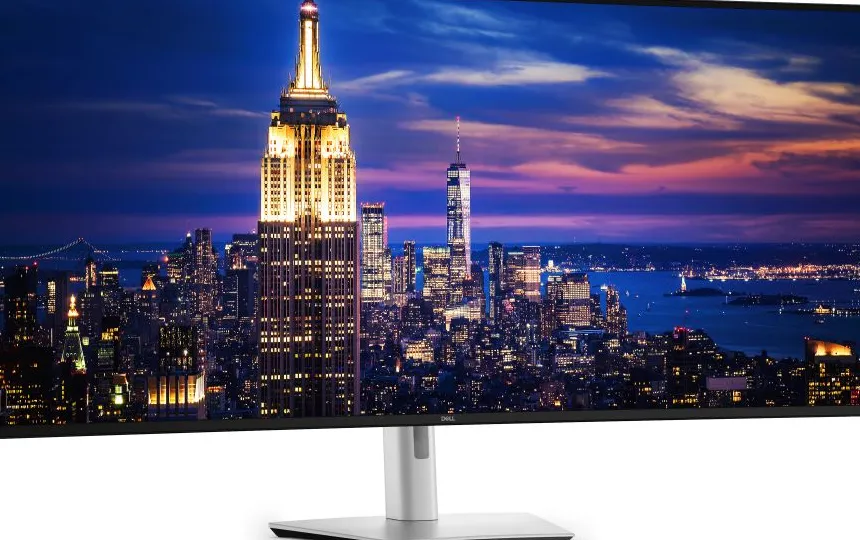 Wide screen monitor displaying a cityscape with a prominent illuminated skyscraper at dusk
